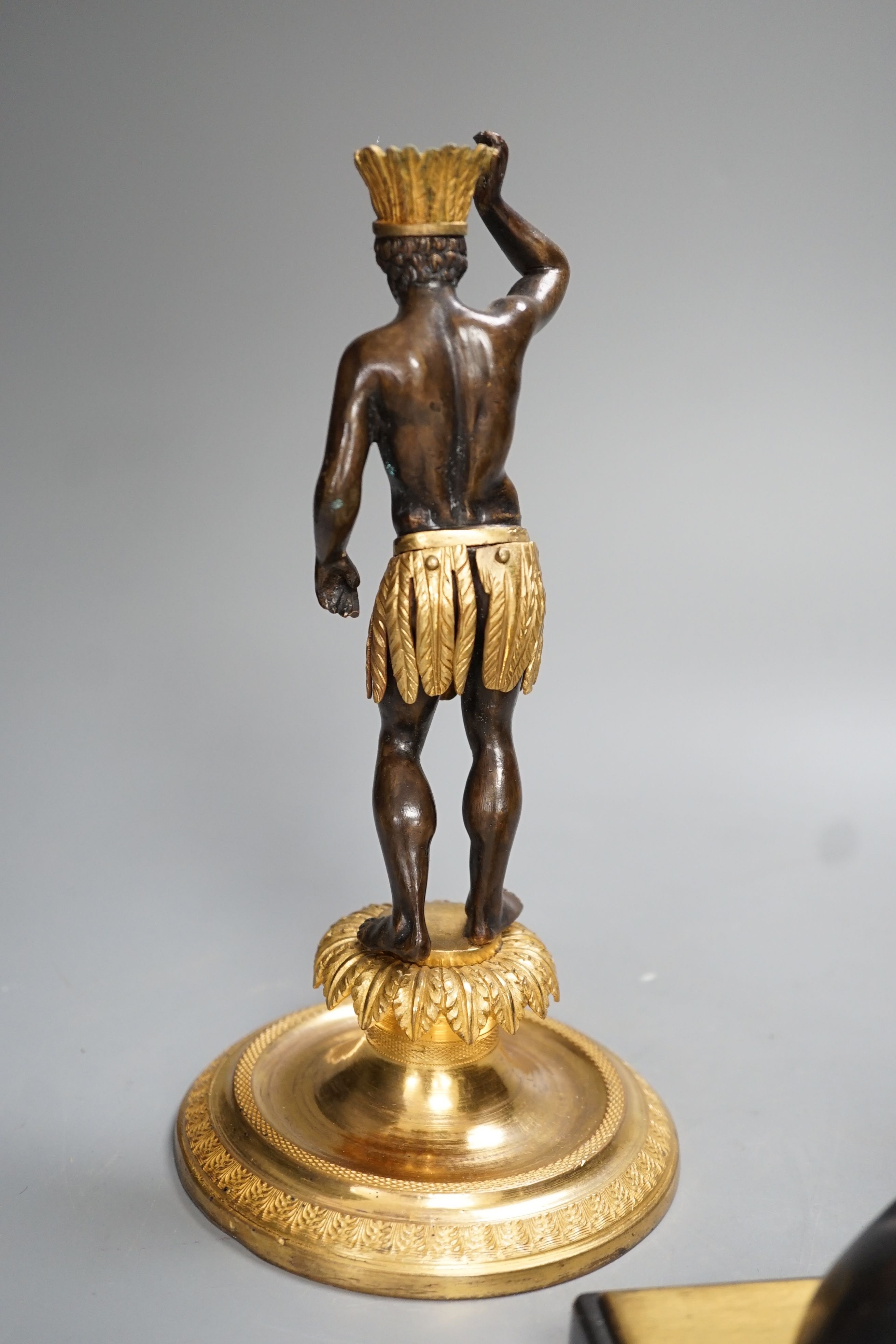 A patinated metal model of a sphinx and a bronze and gilt figure of a Nubian man. 22cm